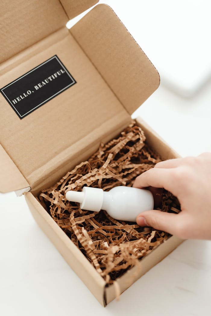 Hand opening cardboard box with eco-friendly filler and dropper bottle.